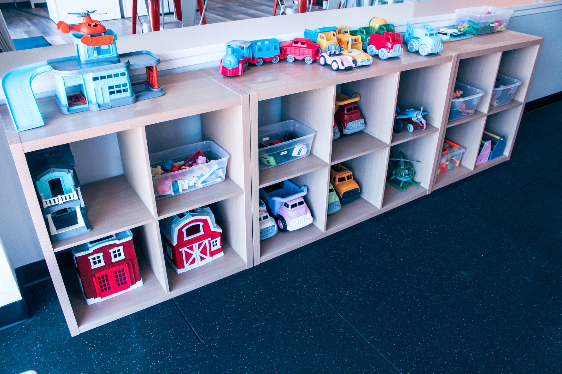 Cubby shelves filled with cars, trucks, trains, and pretend play sets at Little Land New Braunfels