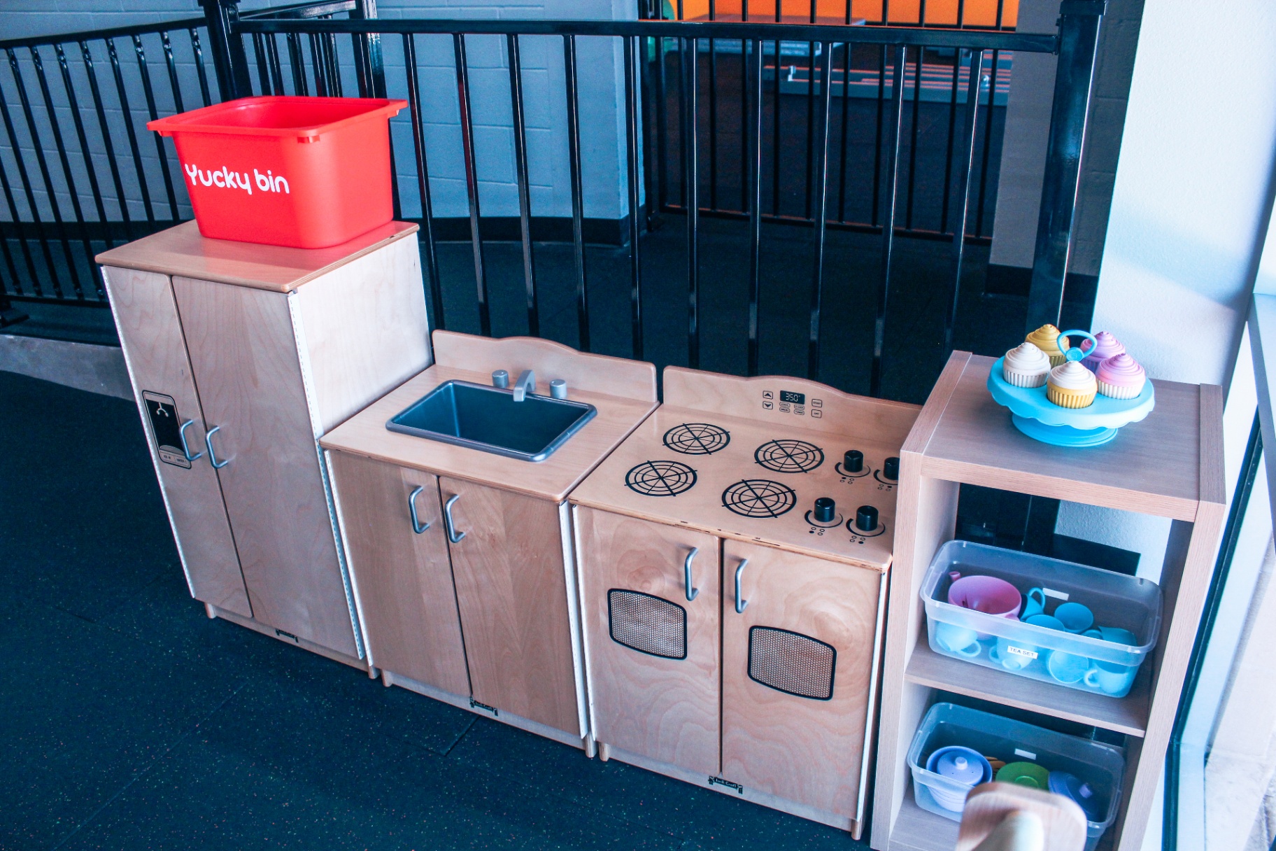 Wooden play kitchen with sink, stove, refrigerator, and cupcake display in the New Braunfels clinic