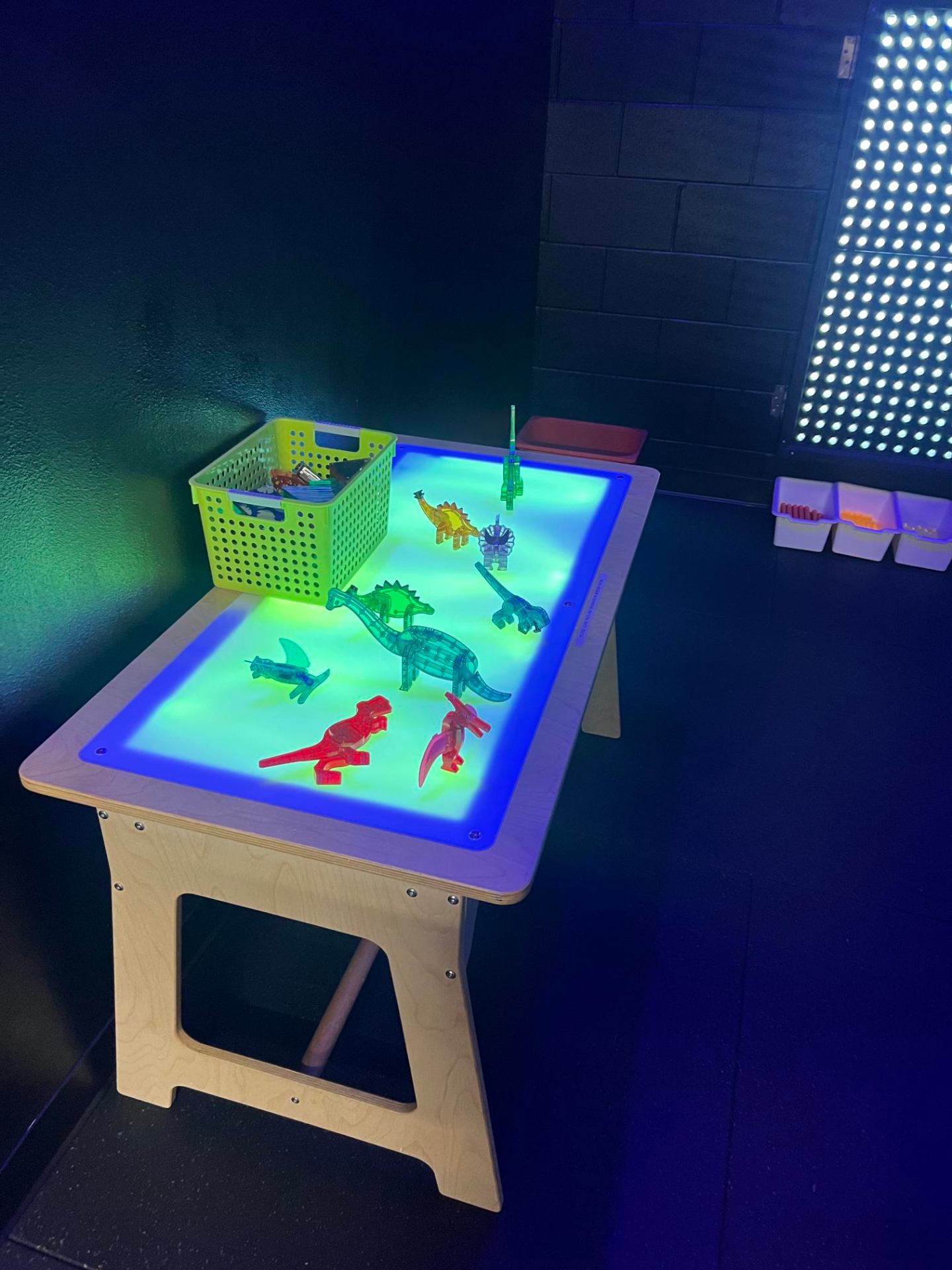 Glowing light table with translucent dinosaur builders in the New Braunfels sensory room