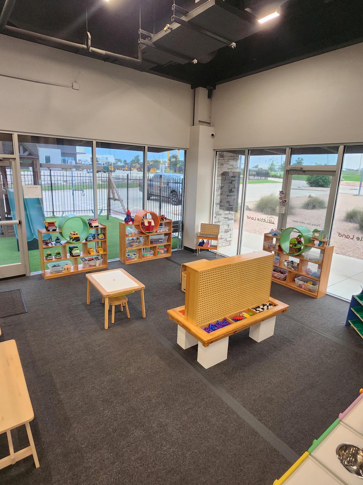 Lobby play space with toy car shelves, sensory tables, and a view of the outdoor playground