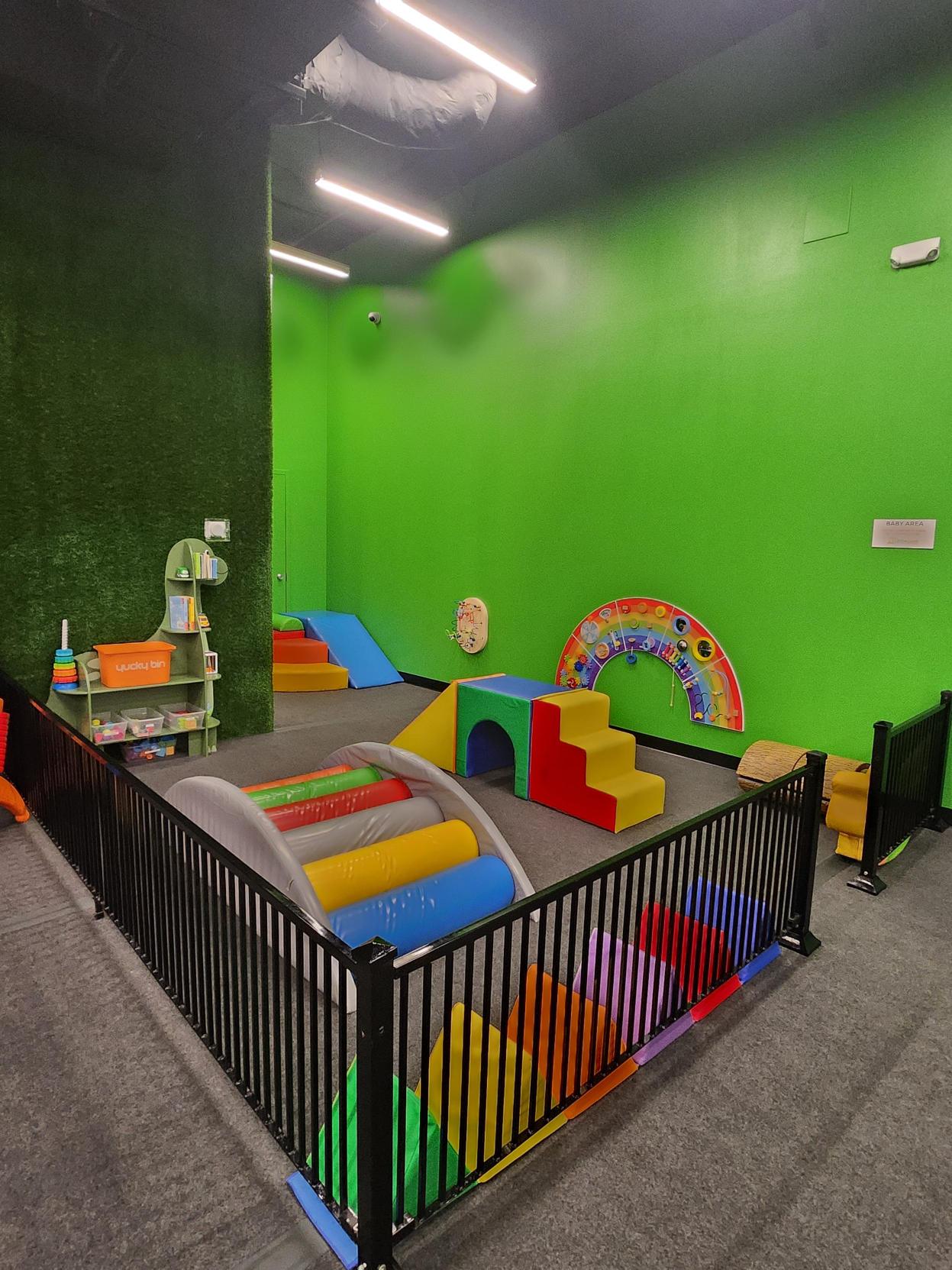 Baby and toddler area with soft foam climbers, tunnels, and a colorful rainbow sensory wall
