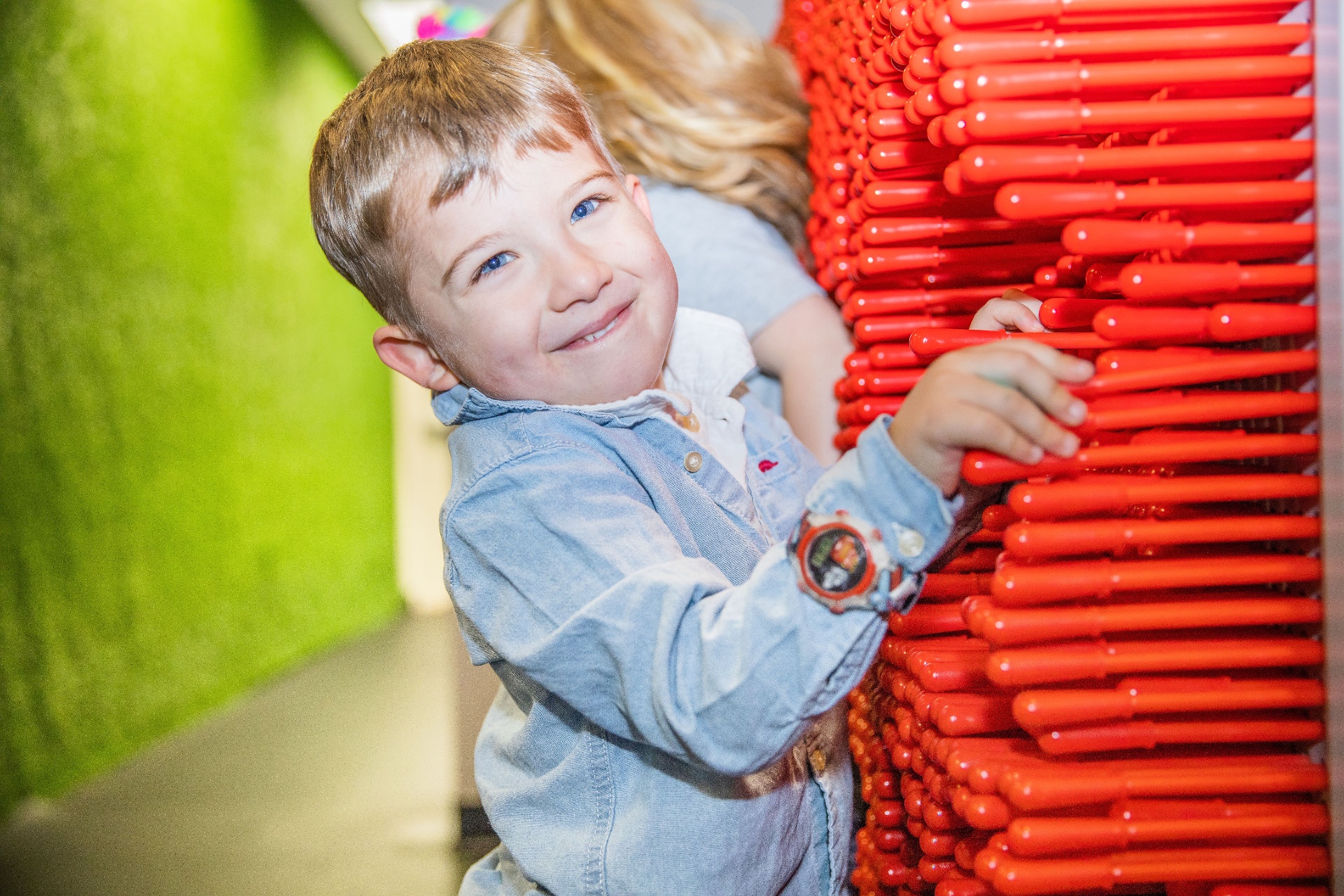Child exploring a bright red sensory wall during camp free play