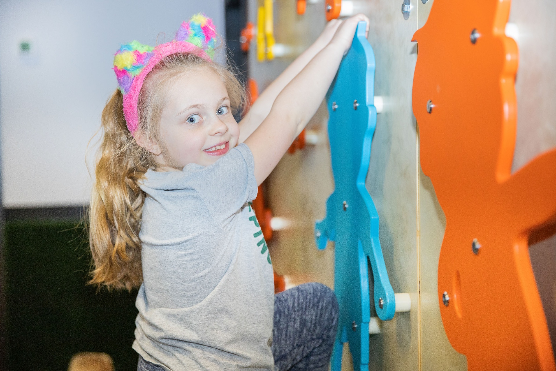 Camper climbing a colorful indoor wall feature during camp
