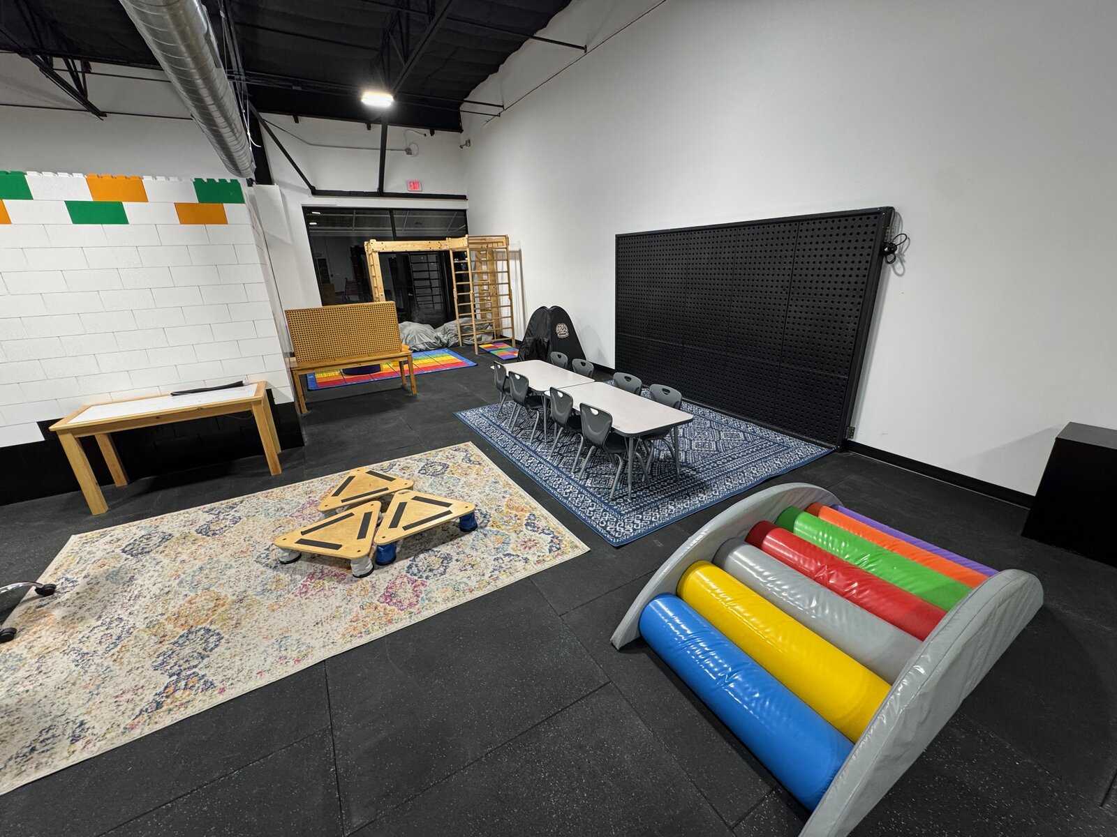 Little Learners classroom at Cedar Park with sensory table, rainbow rocker, pegboard, and student tables