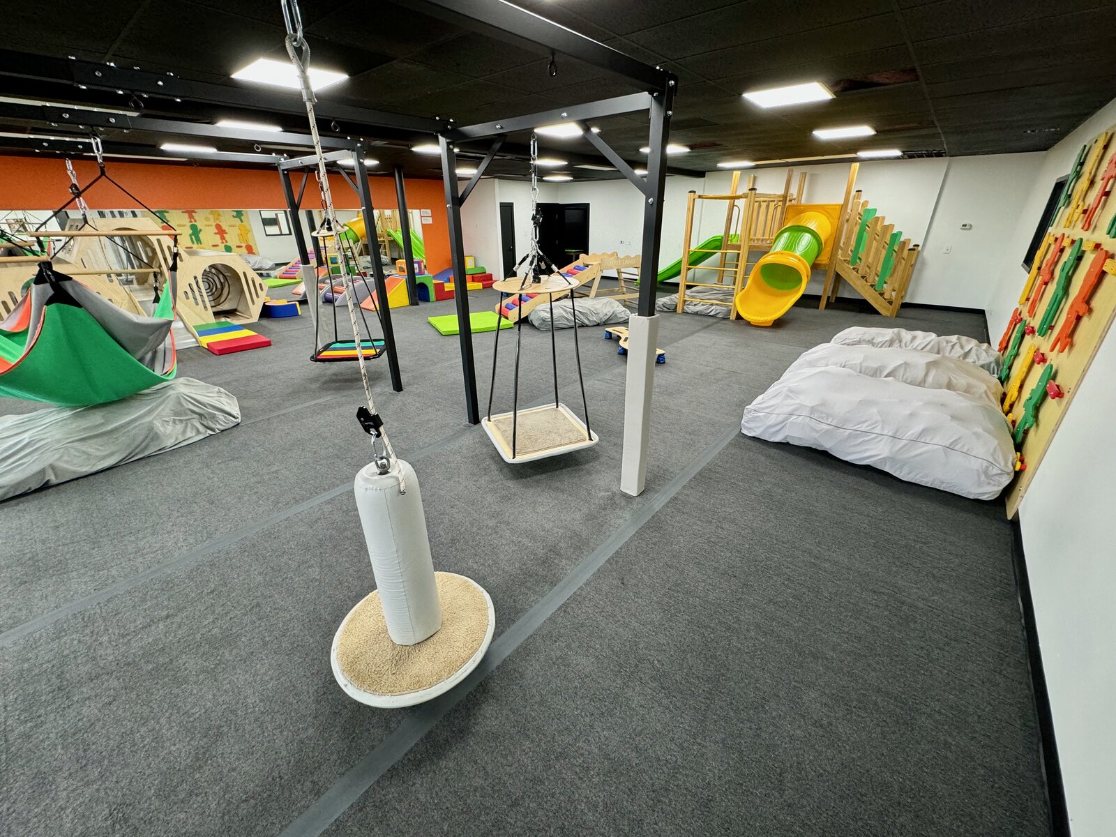 Sensory therapy gym at Little Land Cedar Park with platform swings, hammock, climbers, and a slide