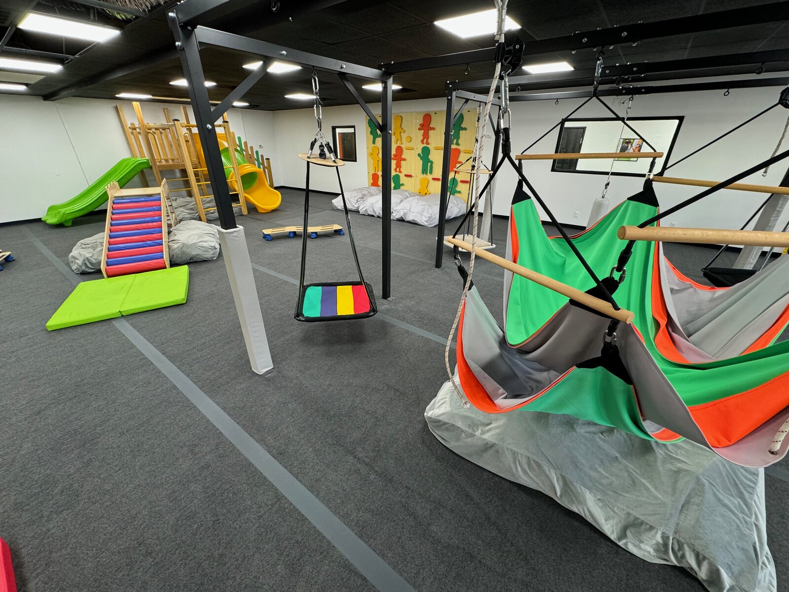 Cuddle swing hammock and rainbow platform swing in the Cedar Park sensory gym