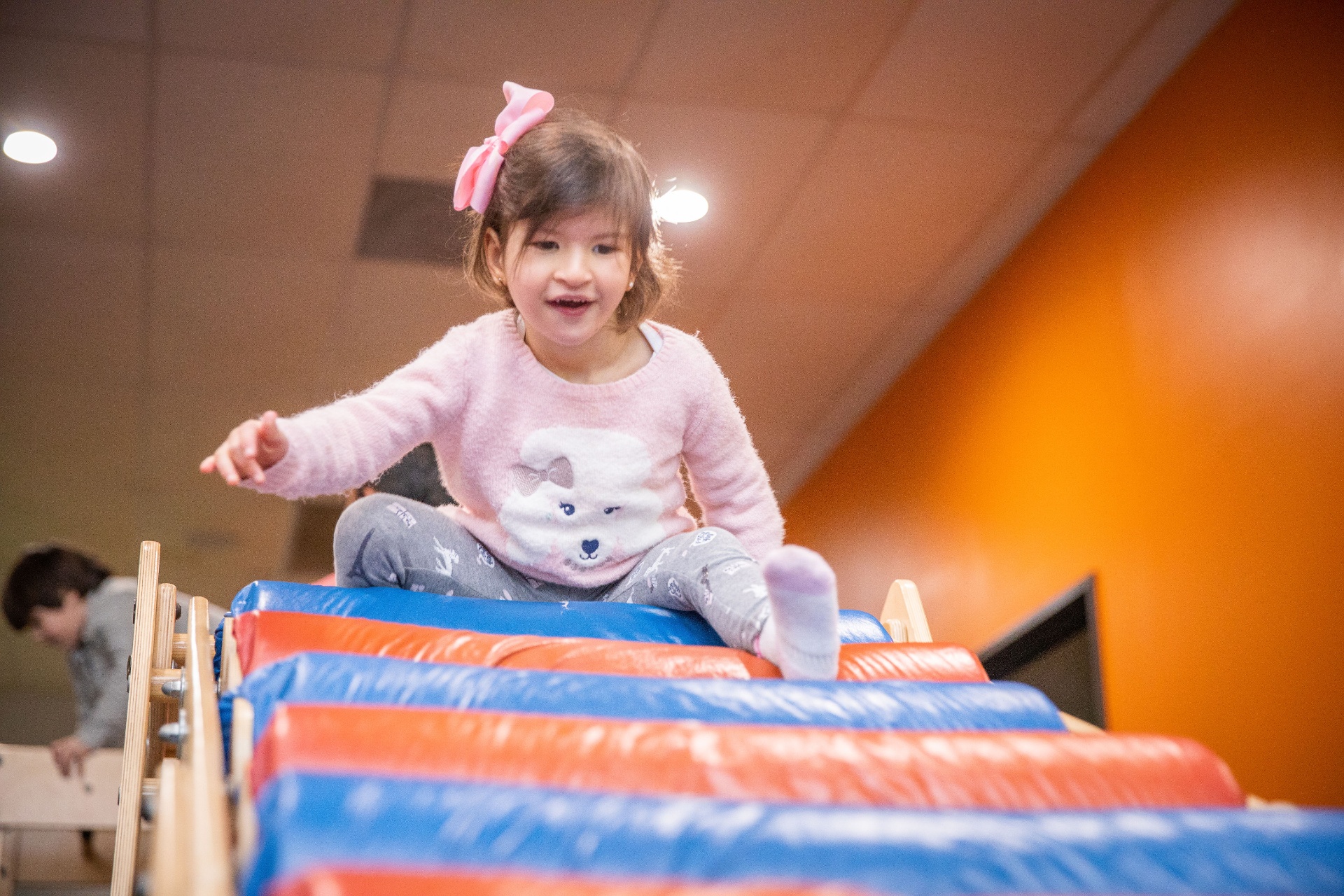 Smiling toddler climbing across padded gym rollers