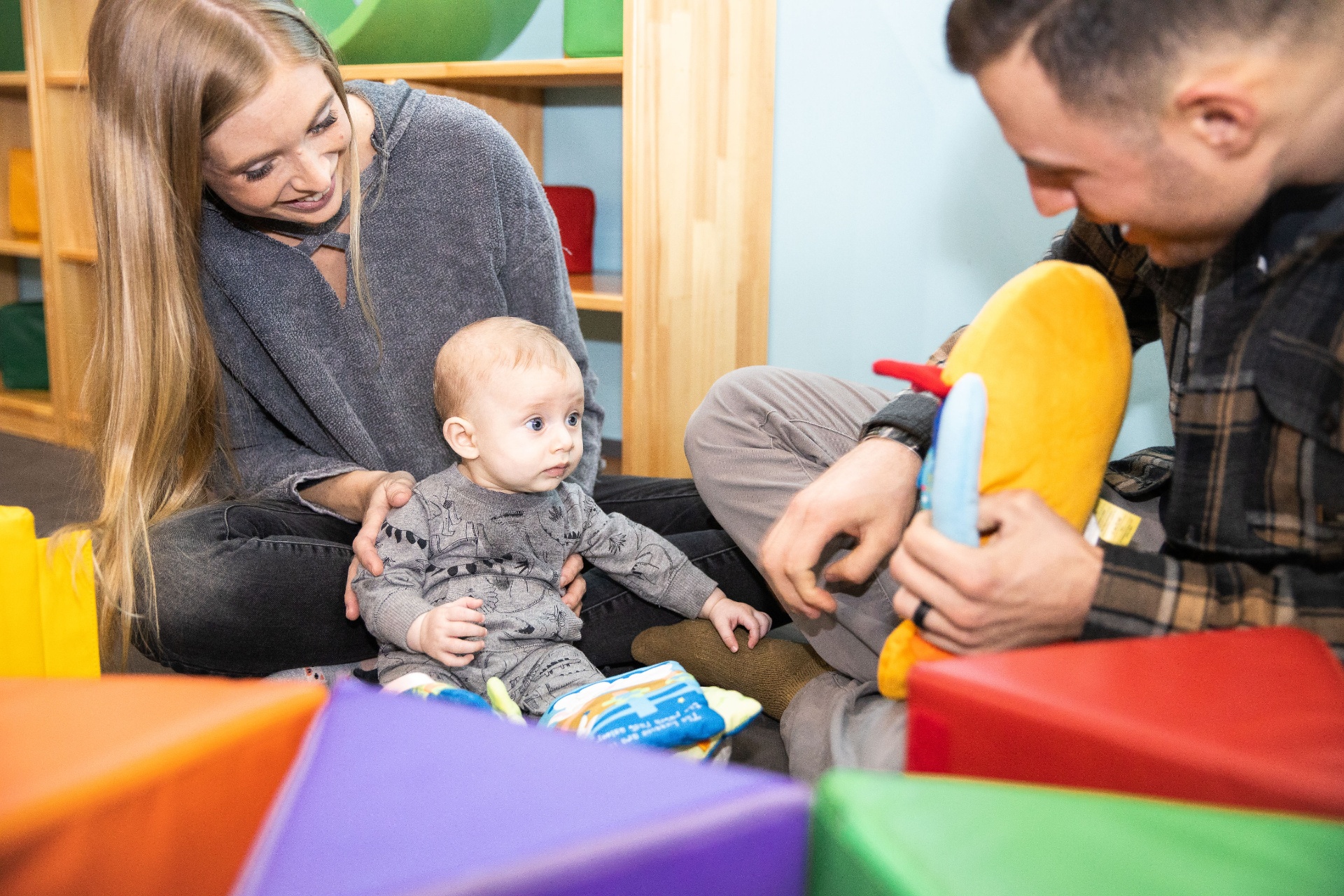 Mom and dad playing on the floor with their baby in the play gym