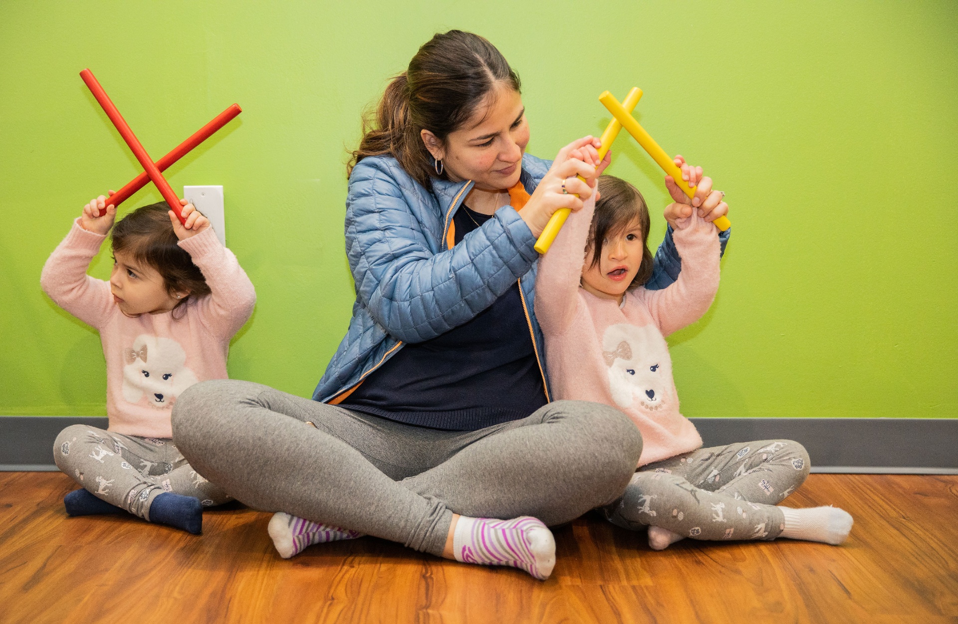 Teacher leading two toddlers in a rhythm-stick activity